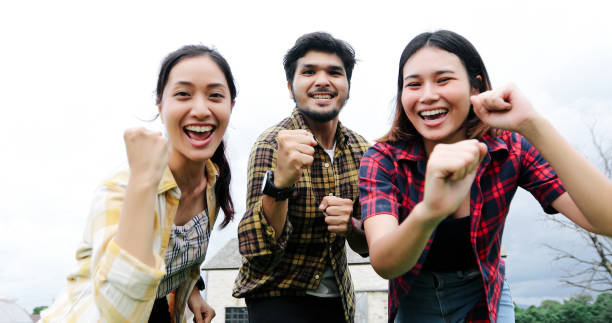 istock Successful Young students at campus looking at camera and smiling and high five while jumping on outdoors. 1158824289