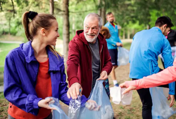 Photo of Group of fit people picking up litter in nature, a plogging concept.