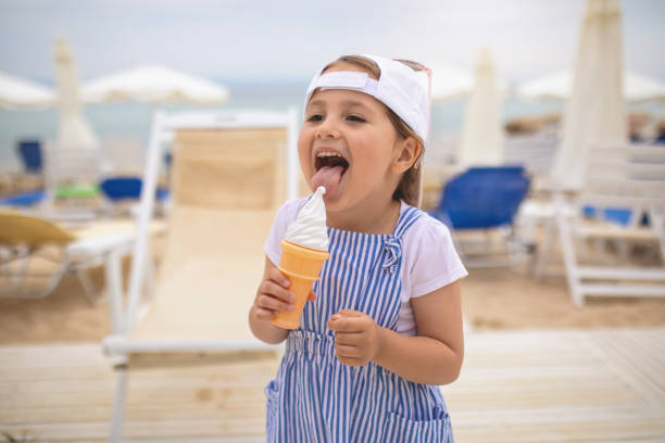 istock Cheerful child licking a vanilla ice cream on the beach 1158824344