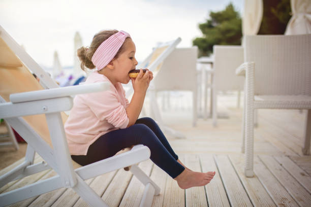 istock Cute child eating a donut on the beach 1158825116