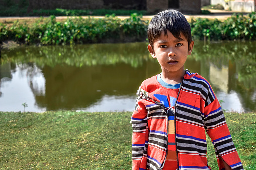 Portrait of an innocent poor boy belonging to the India looking at camera, wearing the traditional dress