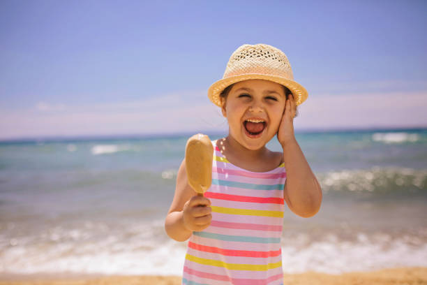 Cute and gorgeous child with a big round hat, enjoying the seaside during summer.