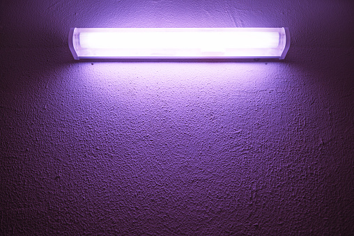 Germicidal ultraviolet lamp glows on a rough wall