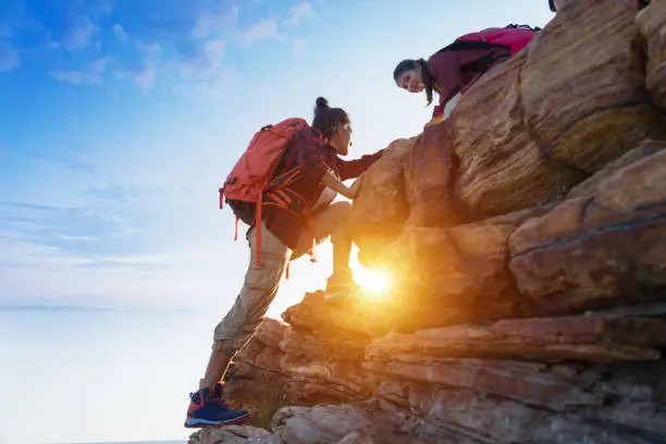 Young asian couple climbing up on the mountain,hiking and team work concept.
