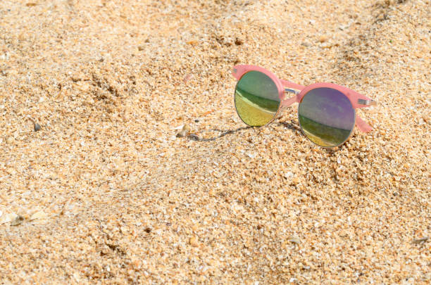 istock Pink sunglasses against the sun on the beach sand 1158832525
