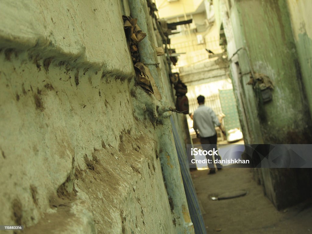 Narrow alley A man walking in a narrow alley in a slum area. Adult Stock Photo