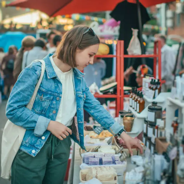 Photo of Young girl exploring organic body care goods at an open-air market with zero waste concept