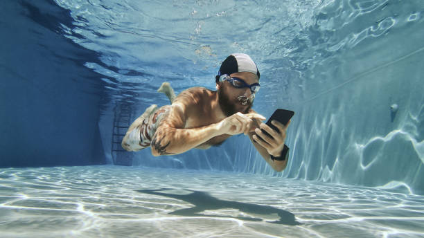 homme bourreau de travail utilisant le téléphone portable sous l'eau - men naked water male photos et images de collection