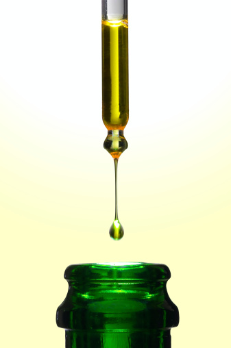 Precious olive oil like liquid gold falling into a bottle.