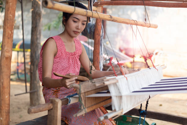 istock Young women weaving with traditional Thai weaving machine 1158842338
