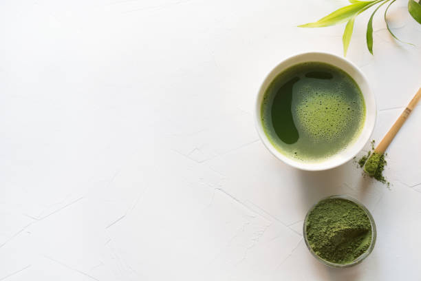 istock Green matcha tea and bamboo whisk on white concrete table. Top view. Copy space. 1158845150