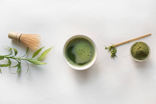 istock Ceremony green matcha tea and bamboo whisk on white concrete table. Top view. 1158845153