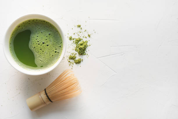 istock Ceremony green matcha tea and bamboo whisk on white concrete table. Top view. Space for text. 1158845168