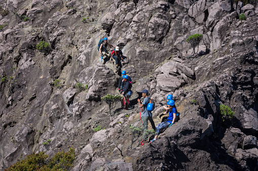 Banyuwangi, Indonesia - June 1, 2019 : A group of hikers and their guide try to conquer chalenging track. Raung is the most extreme and challenging of all Java's mountain trails, Indonesia.