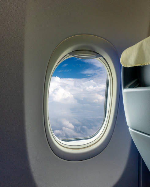 This image shows the view through an airplane window, highlighting the blue sky outside. The image captures the serene moment during a flight, emphasizing travel and journey.