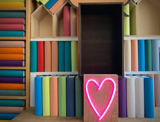 istock Books shelves packed with generic colorful books and a neon heart shape 1158847521