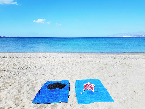 Abandoned blue towels on sandy beach and blue sky