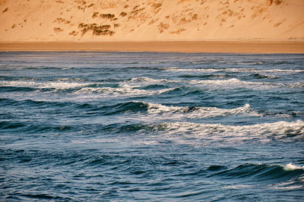 istock Views across the waves to Crantock beach sand dunes on a bright summers evening. 1158847869