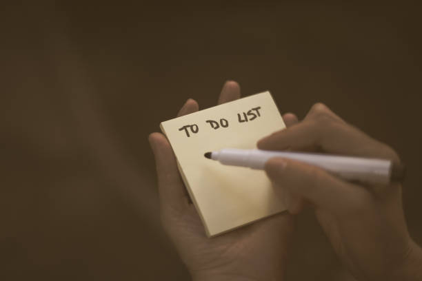 istock Person holding pen and sticky note with the text to do list written on it 1158848814