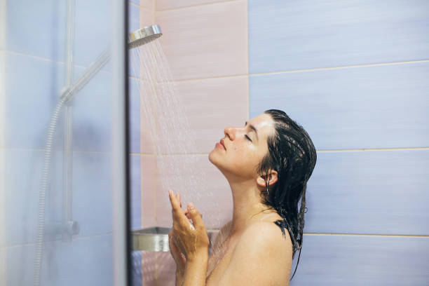 집이나 호텔 욕실에서 샤워를하는 젊은 행복한 여성. 아름다운 갈색 머리 소녀 그녀의 머리를 세척하고 휴식 시간을 즐기고. 신체와 피부 위생, 라이프 스타일 컨셉 - bathtub women naked human face 뉴스 사진 이미지