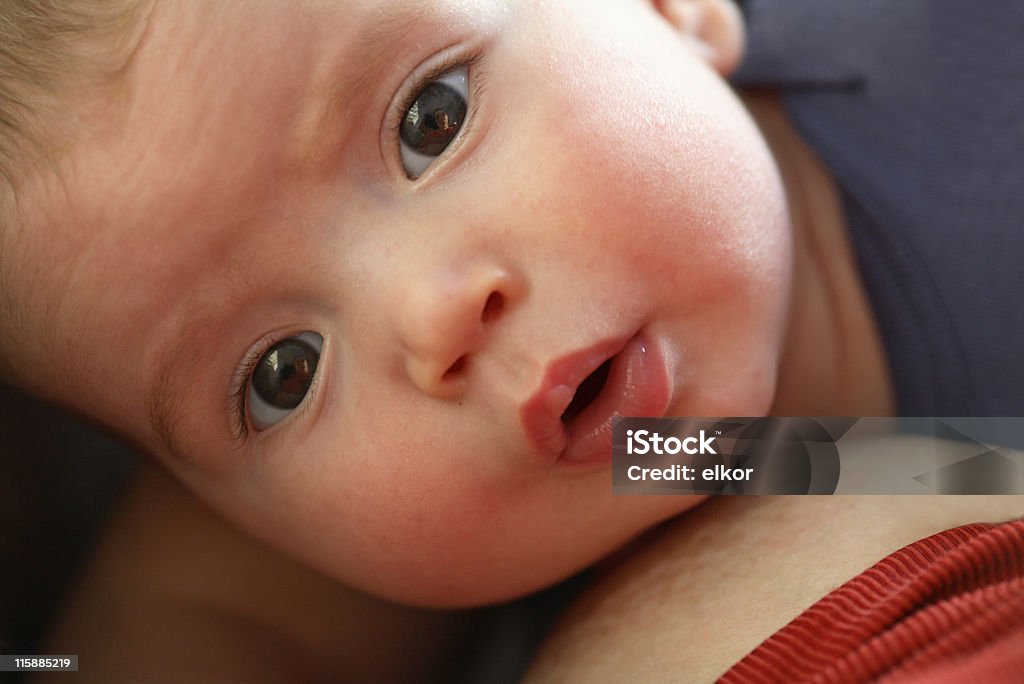 Curious guy Curious baby distructed by the camera during breastfeeding. Mom's reflection in baby's eyes. Adult Stock Photo
