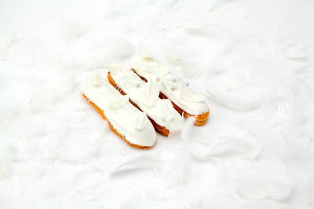A set of three eclairs with white chocolate decor isolate on a white surface decorated with white feathers