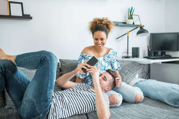 istock Young man surfing the web on smart phone and lying in a young woman's lap 1158854676