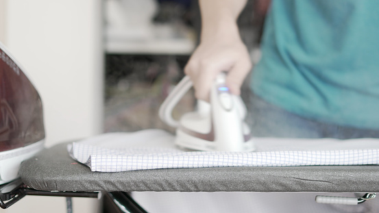 Hand of woman ironing clothes on the table