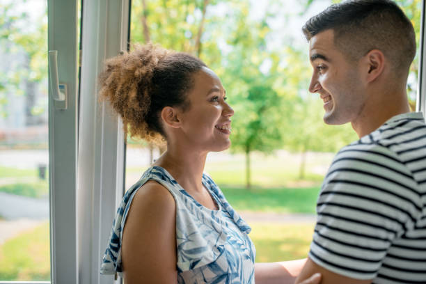 istock Young couple standing in the balcony and embracing each other 1158859634