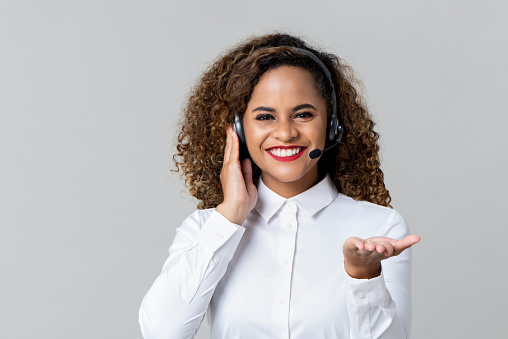 Portrait of happy smiling cheerful African American woman customer support phone operator in headset over gray background