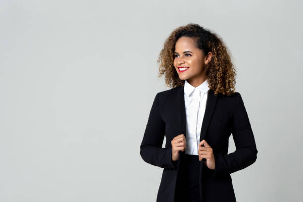 Happy businesswoman in formal clothing Cheerful African American business woman in black suit with curly hair looking away isolated against gray background garment photos stock pictures, royalty-free photos & images