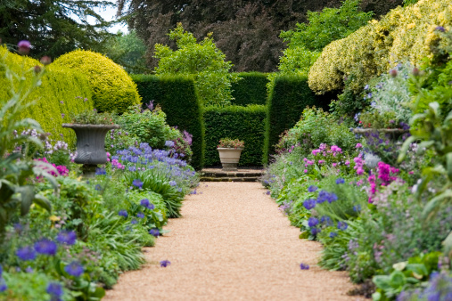 Pathway leading through old fashioned garden borders, shallow depth of field.