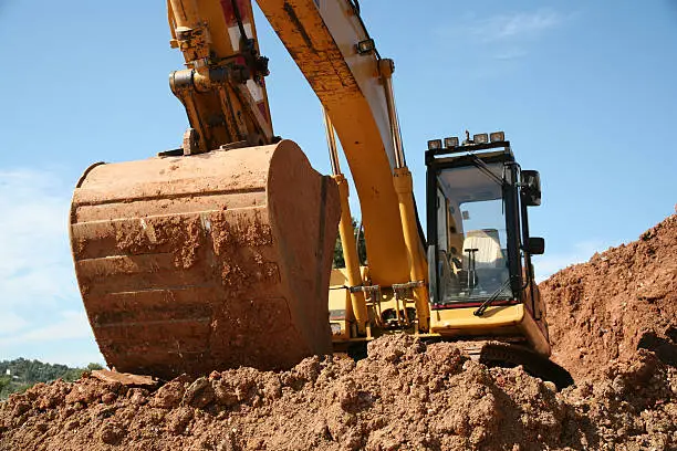A yellow excavator in earthworks.