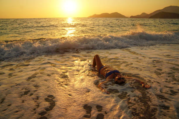 istock Woman having fun with waves at sunset. 1158865001