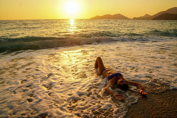 istock Woman having fun with waves at sunset. 1158866550