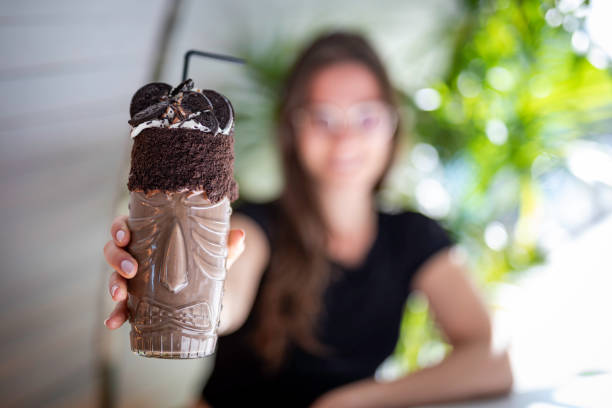 piękne kobiety zamazane trzymając shake czekoladowy i ciasteczka na przezroczystym szkle z aborygenów projekt zbliżenie - milk shake coffee latté cold zdjęcia i obrazy z banku zdjęć