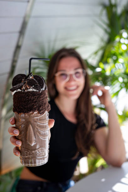 piękne kobiety zamazane trzymając shake czekoladowy i ciasteczka na przezroczystym szkle z aborygenów projekt zbliżenie - milk shake coffee latté cold zdjęcia i obrazy z banku zdjęć