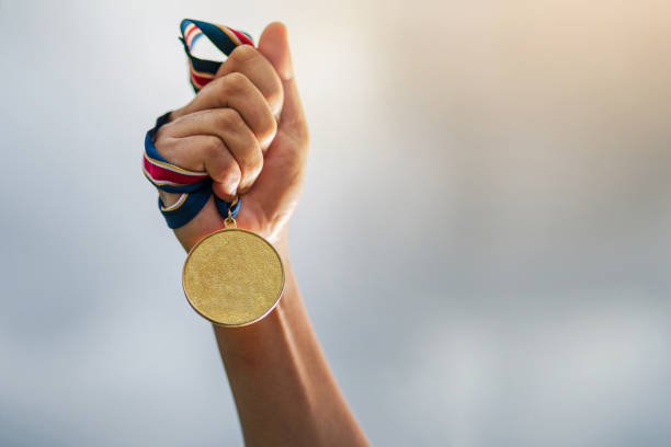 The winner and successful concept Hand holding gold medal on sky background, The winner and successful concept athleticism stock pictures, royalty-free photos & images