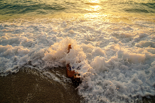 Woman having fun with waves at sunset.