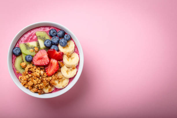 Healthy acai smoothie bowl Summer acai smoothie bowl with strawberries, banana, blueberries, kiwi fruit and granola on pastel pink background. Breakfast bowl with fruit and cereal, close-up, top view, space for text blueberry photos stock pictures, royalty-free photos & images