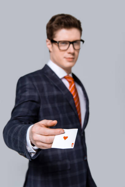 istock selective focus of stylish businessman holding ace isolated on grey 1158873349