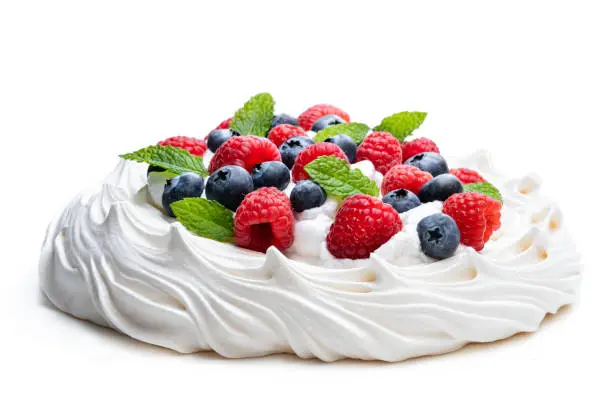 Photo of Pavlova meringue nest with berries and mint leaves isolated on white