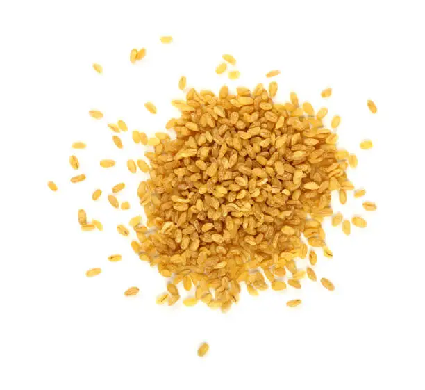 Close up heap of yellow traditional bulgur (bulghur, burghul) big grains of durum wheat, isolated on white background, close up, elevated top view, directly above