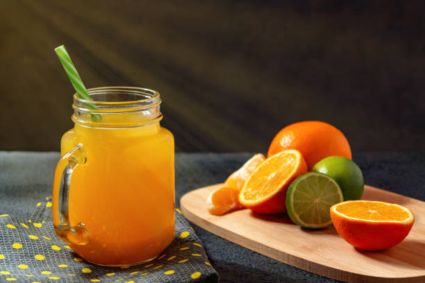 istock Freshly made citrus juice from oranges, grapefruit and lime in a jar-mug with a straw on black table 1158883553