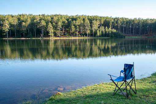 Armchair for fishing on the lake. Fishing rod in the water.