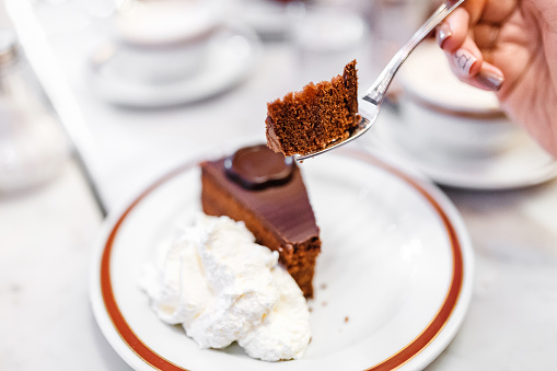 A woman eating a fork in a cafe is a delicious and tasty Sacher cake
