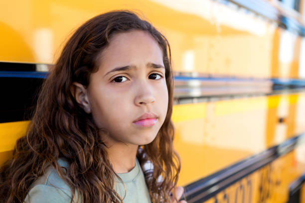 Portrait of sad schoolgirl Lonely school girl looks at the camera. She has a sad facial expression. sad child standing stock pictures, royalty-free photos & images