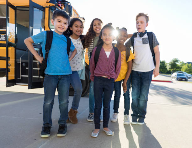 istock Smiling, happy children stand in group by school bus 1158890125