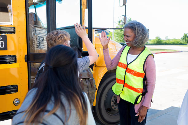 istock Bus driver gives high fives children loading on bus 1158890130
