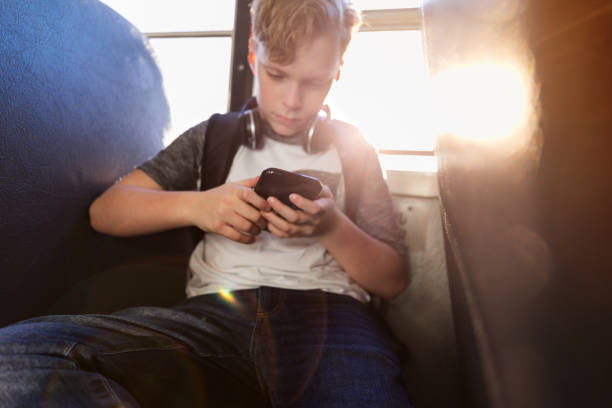 istock Sitting on bus boy checks texts on smart phone 1158890139